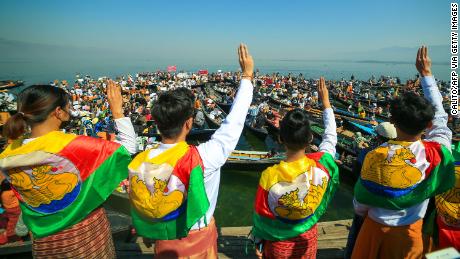 Protesters wearing traditional Shan dress make the three-figner salute as others hold signs during a demonstration against the Myanmar military coup in Inle lake, Shan state on February 11.