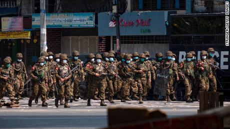 Military soldiers walk down a street with weapons that contain live ammunition after clashes with protesters on March 3 in Yangon, Myanmar. 