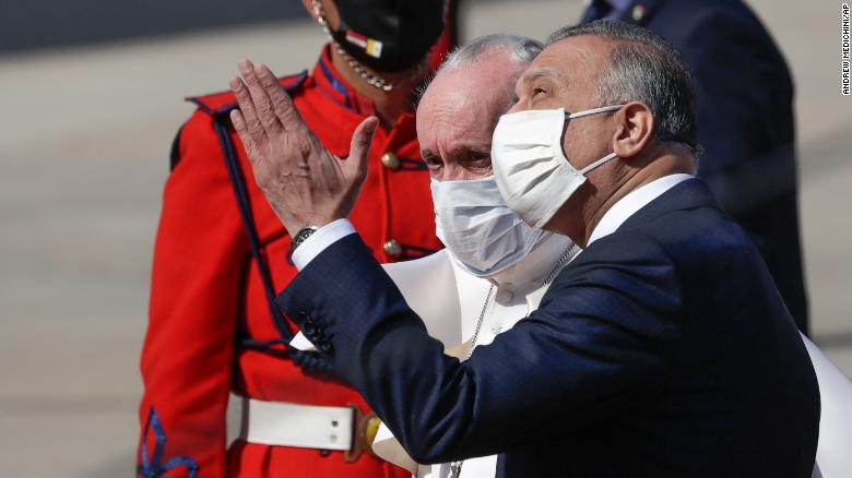 Pope Francis is greeted by Iraqi Prime Minister Mustafa al-Kadhimi as he arrives at Baghdad&#39;s international airport.