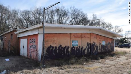 A former car dealership displays a graffiti representation of Bloody Sunday on its boarded facade.