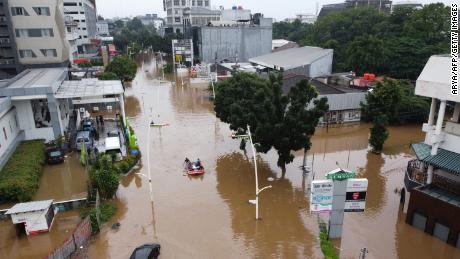 This aerial picture shows people rowing a raft over a flooded road in Jakarta on February 20, 2021, following heavy overnight rains. The combination of so many people and the multitude of rivers has made this city especially prone to relative sea level rise.