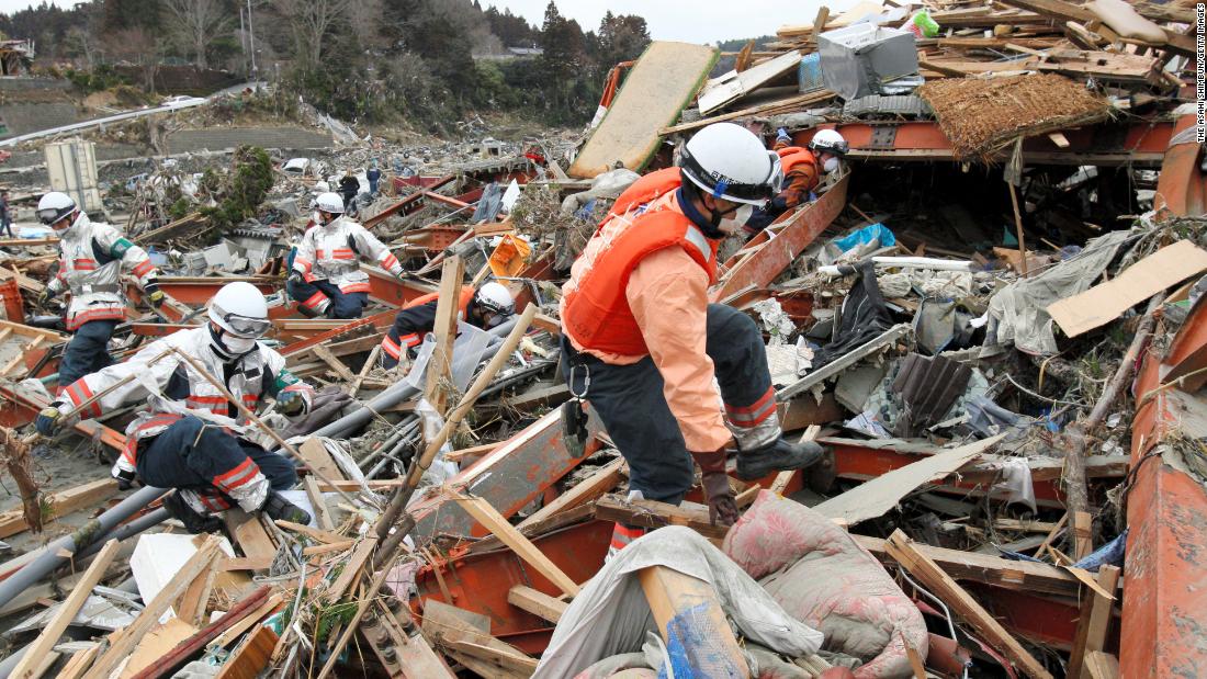 Rescue workers search for survivors among destroyed houses and debris in Minamisenriku, Miyagi prefecture.