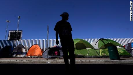 A migrant from Honduras seeking asylum in the United States stands in front of rows of tents at the border crossing, Monday, March 1, 2021, in Tijuana, Mexico. President Joe Biden is holding a virtual meeting with Mexican President Andrés Manuel López Obrador. Monday&#39;s meeting was a chance for them to discuss migration, among other issues. (AP Photo/Gregory Bull)