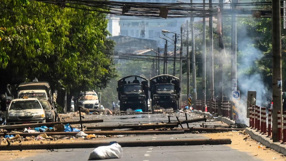 Military trucks are seen near a burning barricade in Yangon that was erected by protesters and then set on fire by soldiers on March 10.