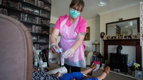 Dawn, a carer from Elite Care Solutions gives her client Tina, who suffers with Multiple Sclerosis and is considered in the high risk category during the current novel coronavirus COVID-19 pandemic, her lunchtime feed via a tube during a home visit in Scunthorpe, northern England on May 8, 2020. - Home carers are an essential key worker service to those with disabilities stranded at home under the lockdown, providing specialist care and human kindness.  Dawn has worked with Tina for seven years and although Tina&#39;s disabilities limit her outdoor recreation, she misses most of all her and Dawn&#39;s visits to the local park for their weekly latte drink. (Photo by Lindsey Parnaby / AFP) (Photo by LINDSEY PARNABY/AFP via Getty Images)