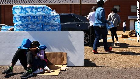 A brother and sister sit while their mother volunteers at a water and food distribution drive in Jackson, Mississippi after the city was hit by back-to-back winter storms. 