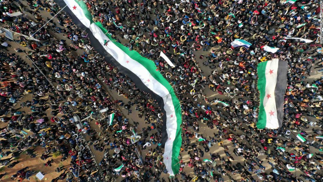 An aerial picture shows Syrians waving the national flag during a gathering in the rebel-held city of Idlib on March 15, 2021, as they mark &lt;a href=&quot;https://edition.cnn.com/2021/03/15/middleeast/syria-anniversary-damon-analysis-intl/index.html&quot; target=&quot;_blank&quot;&gt;10 years&lt;/a&gt; since the nationwide anti-government protests that sparked the country&#39;s devastating civil war.