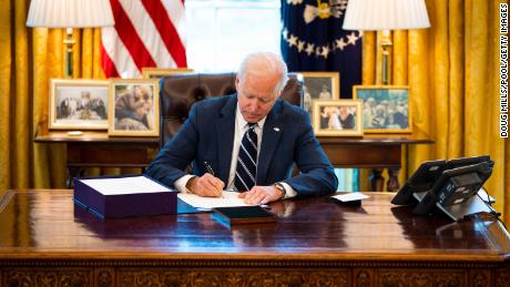 President Joe Biden signs  the $1.9 trillion Covid relief bill into law in the Oval Office of the White House on Thursday, March 11, in Washington