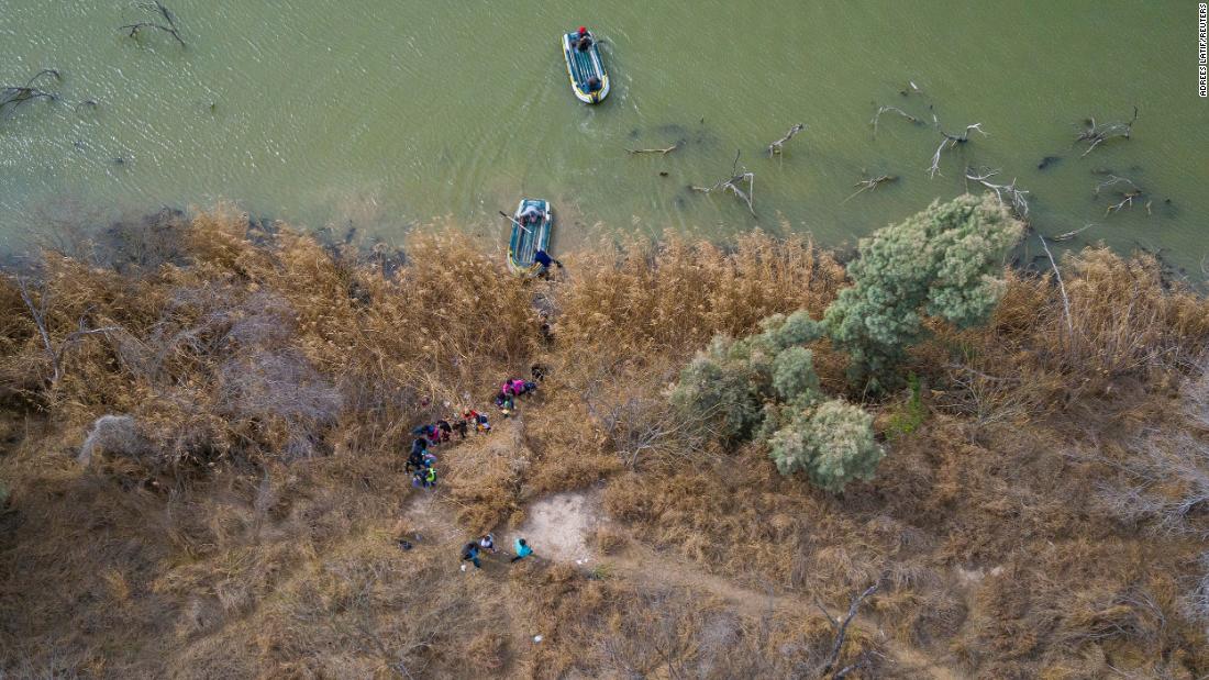 Migrants climb the banks of the Rio Grande into the United States as smugglers on rafts prepare to return to Mexico on March 5.