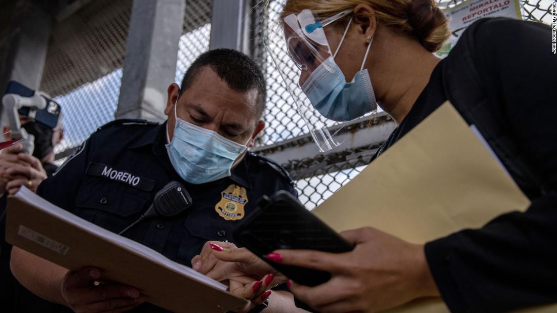  A US Customs and Border Protection officer checks for the name of a migrant as a group of at least 25 asylum seekers were allowed to travel from a migrant camp in Mexico into the United States on February 25. The group was the first allowed to cross into south Texas as part of the unwinding of the Trump administration&#39;s Migrant Protection Protocols. Many of the asylum seekers had been waiting in a squalid camp alongside the Rio Grande for more than a year.