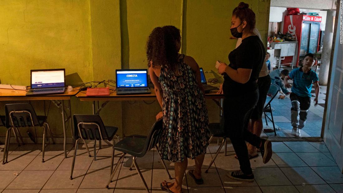 Emma Moreno, right, a volunteer working at the Agape shelter in Tijuana, helps an asylum seeker check the &quot;Conecta&quot; website of the United Nations High Commissioner for Refugees. &quot;Conecta&quot; allows asylum seekers who&#39;ve been stuck in Mexico under the Migrant Protection Protocols to enter the United States and wait there for their asylum process. On the first day of the rollout, the website quickly became oversaturated as the estimated 25,000 people in the program attempted to register. 