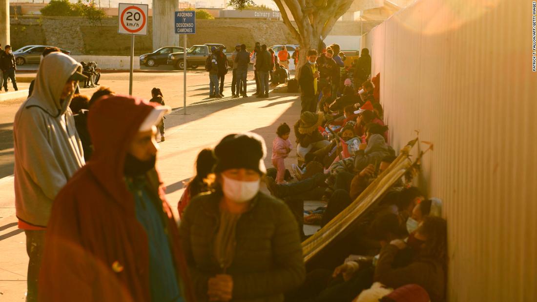 Asylum seekers wait outside the El Chaparral border crossing port as they wait to cross into the United States from Tijuana on February 19. The Biden administration is still turning back most migrants at the border, but officials are gradually allowing 25,000 people previously enrolled in the Migrant Protection Protocols program to cross into the United States.