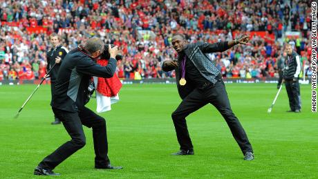 Usain Bolt recreates his famous celebration on the pitch at Old Trafford.