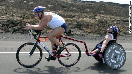 Dick Hoyt and his son Rick cross the lava desert during the cycling test of the 27th Iron Man Competition in Kailua-Kona, Hawaii, on October 18, 2003.