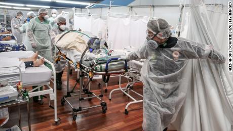 SANTO ANDRE, BRAZIL - MARCH 11: Medical staff members transport a patient on a stretcher at the Pedro DellAntonia Sports Complex field hospital as coronavirus cases soar on March 11, 2021 in Santo Andre, Brazil. The state of Sao Paulo has reached over 80% occupancy in intensive care units and has declared a red alert as the spread of COVID-19 has accelerated in Brazil in recent weeks. State Health Minister Jean Gorinchteyn announced that they are already recruiting health professionals for reinforcement and working in 140 extra ICUs to prevent the collapse of the health system. 38 patients with COVID-19 have already died on the waiting list for ICU&#39;s beds in the state in the first ten days of March. (Photo by Alexandre Schneider/Getty Images)