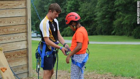Summer camps have been planning with Covid-19 protocols in mind. In this August 2017 photo, staffer Joe Gilligan helps a camper with safety gear at Camp Sloane YMCA in Lakeville, Connecticut. The camp did not offer programs in 2020.