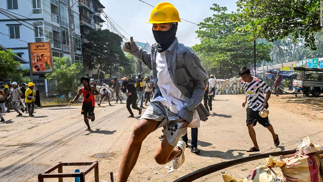 An anti-coup protester jumps over a makeshift barricade in Yangon on Friday, March 19.