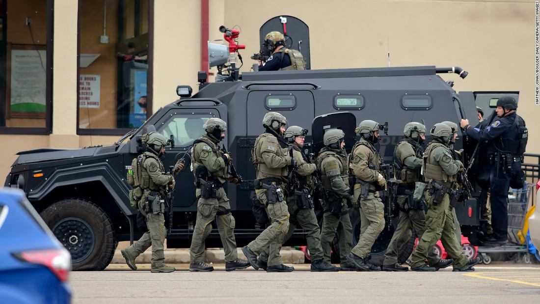 Police use an armored vehicle as a shield to move from one side of the building to the other.