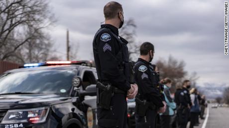 Des membres du département de police de Boulder bordent la route alors que des véhicules escortent Talley jusqu'à un salon funéraire.