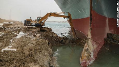 An excavator attempts to free the front end of the Ever Given.