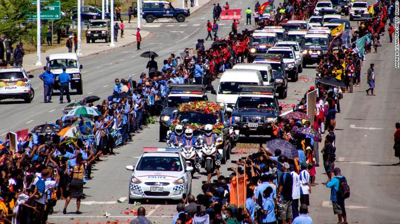 La gente hace fila mientras la policía escolta un coche fúnebre que transporta el ataúd del primer primer ministro de Papúa Nueva Guinea, Michael Somare, en Port Moresby el 11 de marzo.