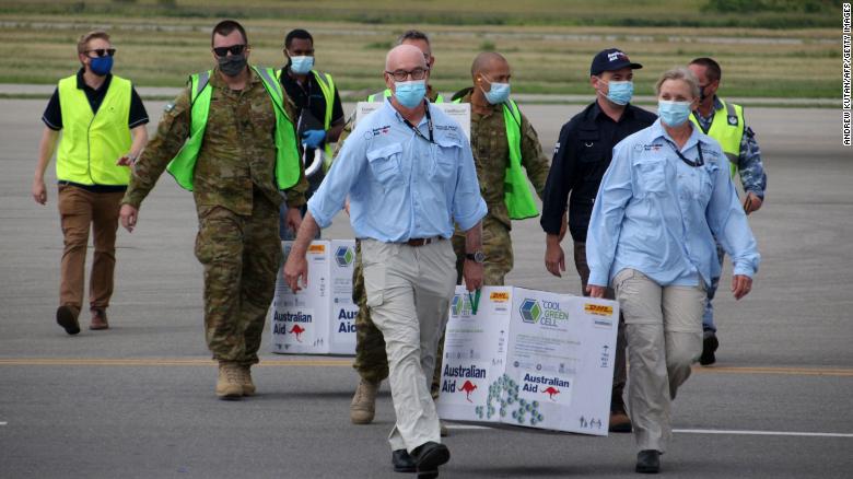 Los funcionarios australianos llevan cajas que contienen unas 8.000 dosis iniciales de la vacuna AstraZeneca en el aeropuerto internacional de Port Moresby el 23 de marzo. 