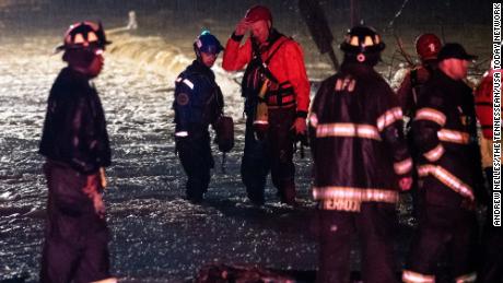 Emergency personnel gather after responding to a call to help people stranded in the water on Antioch Pike in Nashville on Sunday.