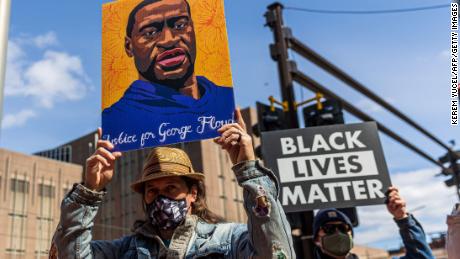 Demonstrators hold signs honoring George Floyd and other victims during a protest outside Hennepin County Government Center on March 28, 2021 in Minneapolis.