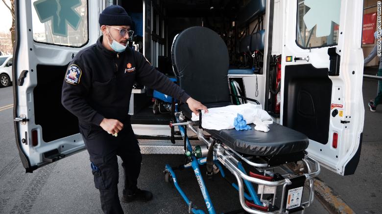 An EMT worker cleans a gurney after transporting a suspected Covid-19 patient outside of a Brooklyn hospital on March 29 in New York.