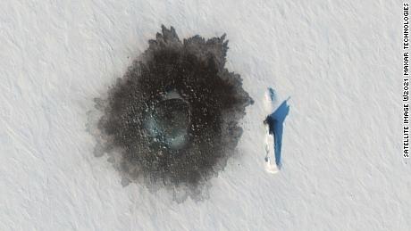 A Russian Delta IV submarine photographed on top of ice near Alexandra Island on March 27, during an exercise, with a likely hole blown in the ice to its left from underwater demolition.