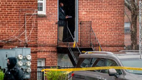 A detective stands at the door of an apartment building taped up at the scene of a shooting in the Congress Heights neighborhood of Washington, DC on Wednesday, March 31.