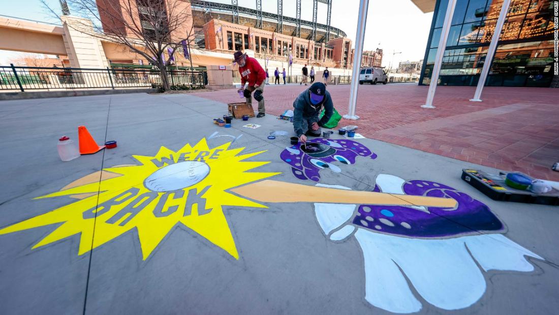 Artists Kyle Banister, left, and Eric Matelski paint a mural near Coors Field in Denver.