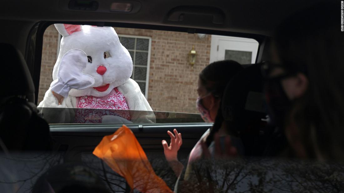 A person dressed as the Easter Bunny greets children in a vehicle during a drive-thru event in Alexandria, Virginia, on March 27.