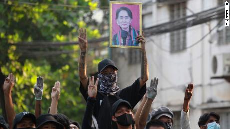 Anti-coup demonstrators raise the three finger of resistance and a portrait of deposed leader Aung San Suu Kyi as prepare to confront police during a protest in Tarmwe township, Yangon on April 1.