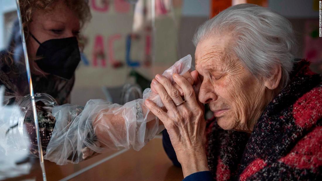 Anna, a resident of the Villa Sacra Famiglia Nursing Home, holds her daughter&#39;s hand in the Rome facility&#39;s &quot;hug room&quot; on February 24. The room allows residents and their families to touch one another while staying safe from Covid-19.