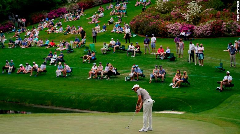 People spread out from one another as they watch Tommy Fleetwood putt on the 16th green on April 9.