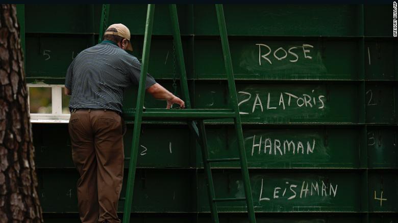 An attendant adjusts the scores of golfers from behind a leaderboard during round three of the Masters on Saturday, April 10.