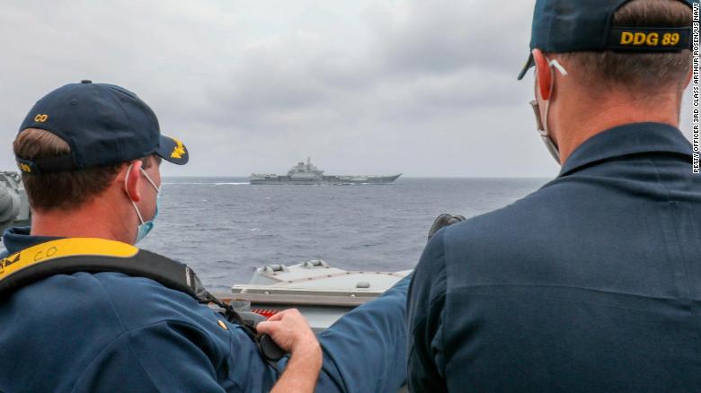 US Navy Cmdr. Robert Briggs and Cmdr. Richard Slye monitor the Chinese aircraft carrier Liaoning from the pilothouse of the guided-missile destroyer USS Mustin on April 4 in the Philippine Sea.