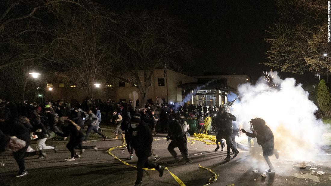 People run as police try to disperse a crowd at the Brooklyn Center Police Department on Sunday.