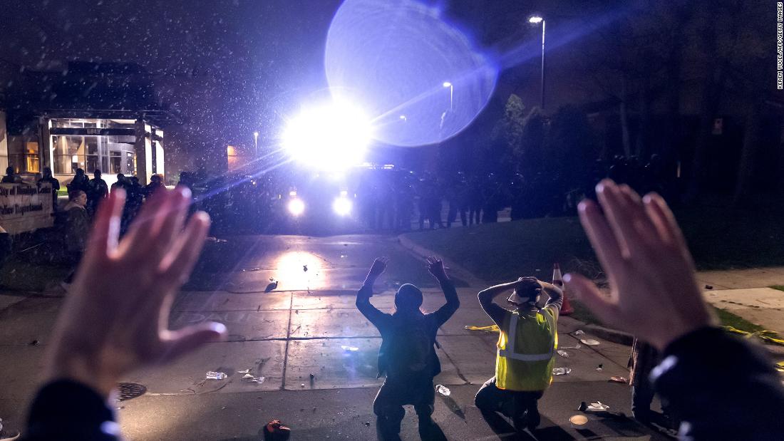 Protesters shout &quot;don&#39;t shoot&quot; while kneeling and raising their arms in front of police on Sunday.