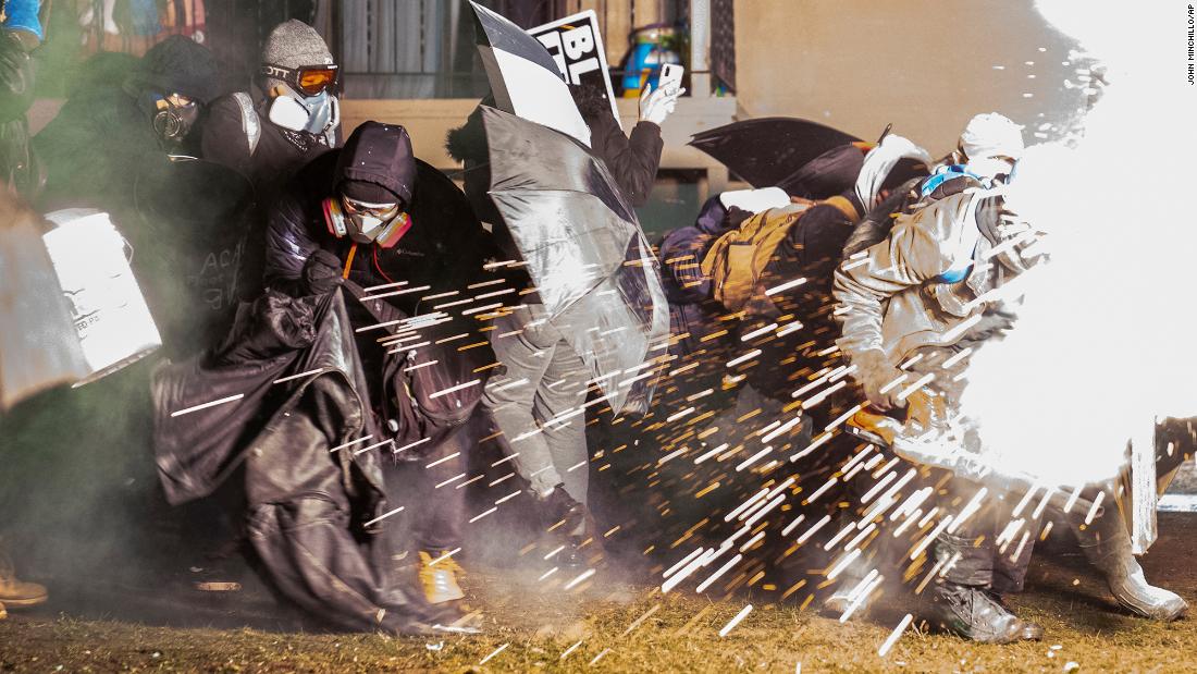 Demonstrators take cover from crowd-dispersal munitions that were deployed outside the Brooklyn Center Police Department on Tuesday.