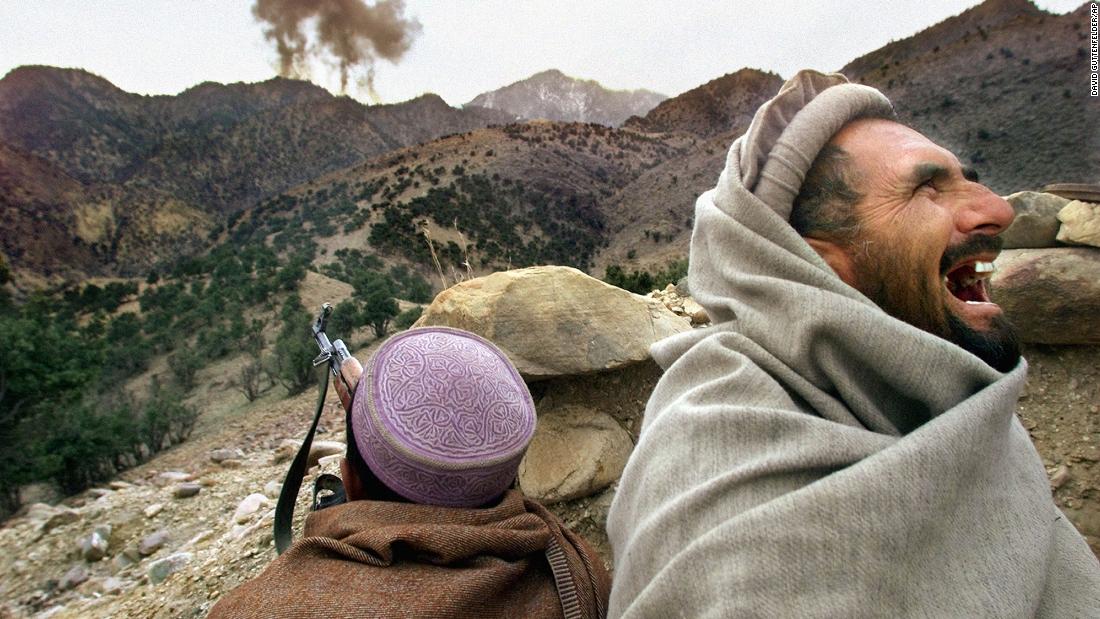 An Afghan Northern Alliance fighter bursts into laughter as US planes strike a Taliban position near Tora Bora, Afghanistan, in December 2001. Afghan militia leaders declared victory in the battle of Tora Bora and claimed to have captured al Qaeda&#39;s last base.