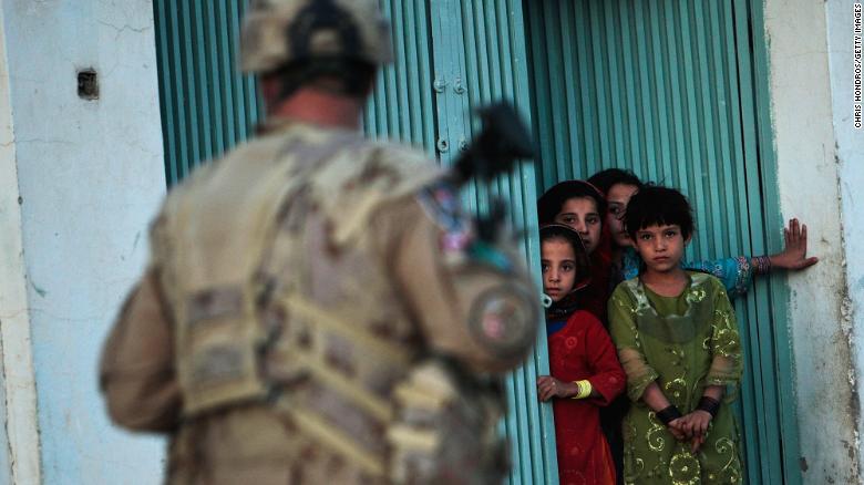 Children watch a Canadian soldier conducting a dusk patrol in Kandahar, Afghanistan, in October 2009.