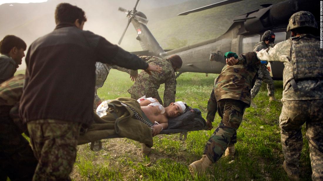 Afghan soldiers rush a wounded police officer to an American helicopter in Afghanistan's Kunar province in March 2010.