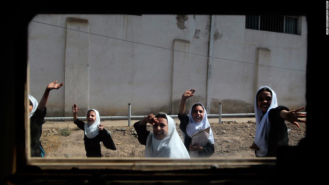 Schoolgirls are seen through the window of a Humvee as they wave to a passing American convoy in Herat, Afghanistan, in June 2010.