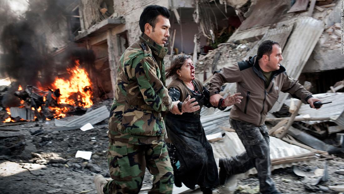 A woman is rushed from the scene of a suicide car bombing in Kabul in December 2013.