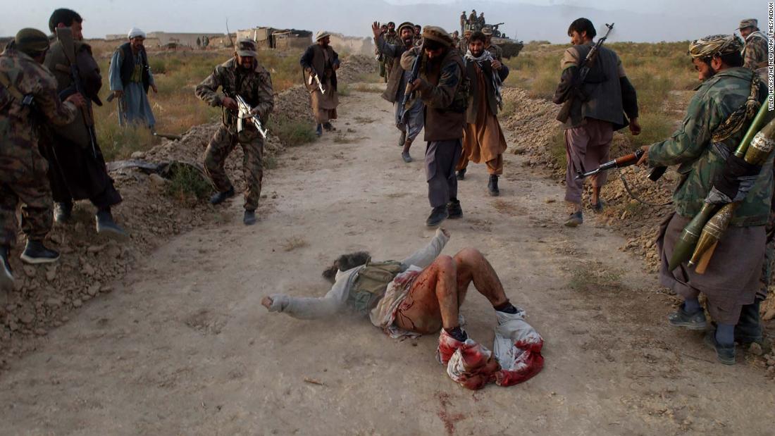 Members of the Afghan Northern Alliance, an anti-Taliban group, kill a wounded Taliban fighter they found while advancing toward Kabul, Afghanistan, in November 2001. US airstrikes and Northern Alliance ground attacks led to the fall of Kabul that month.