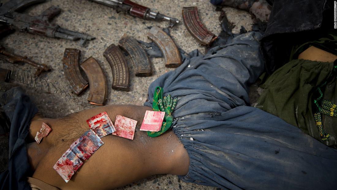 Blood-stained Pakistani bank notes are displayed on the body of a dead suicide bomber after an attack in Kandahar, Afghanistan, in March 2014. Police said they found the bank notes in his pocket. Three insurgents tried to storm the former headquarters of Afghanistan's intelligence service in southern Kandahar. They died in a gunbattle with security forces, officials said.