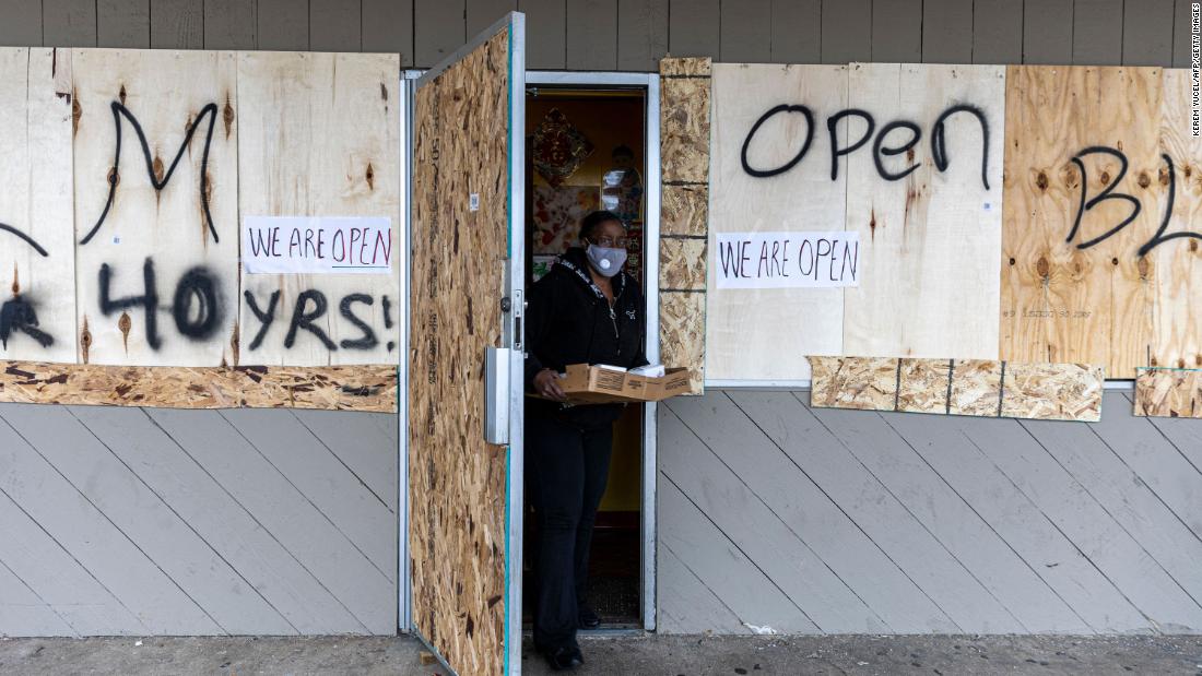 A customer steps out of a store Wednesday that was boarded up as a result of the previous night&#39;s unrest.