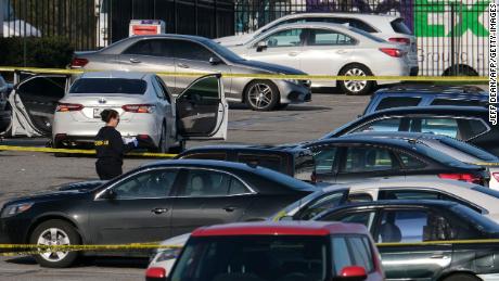 A crime lab technician works Friday in the parking lot of the site of the mass shooting at a FedEx facility in Indianapolis.